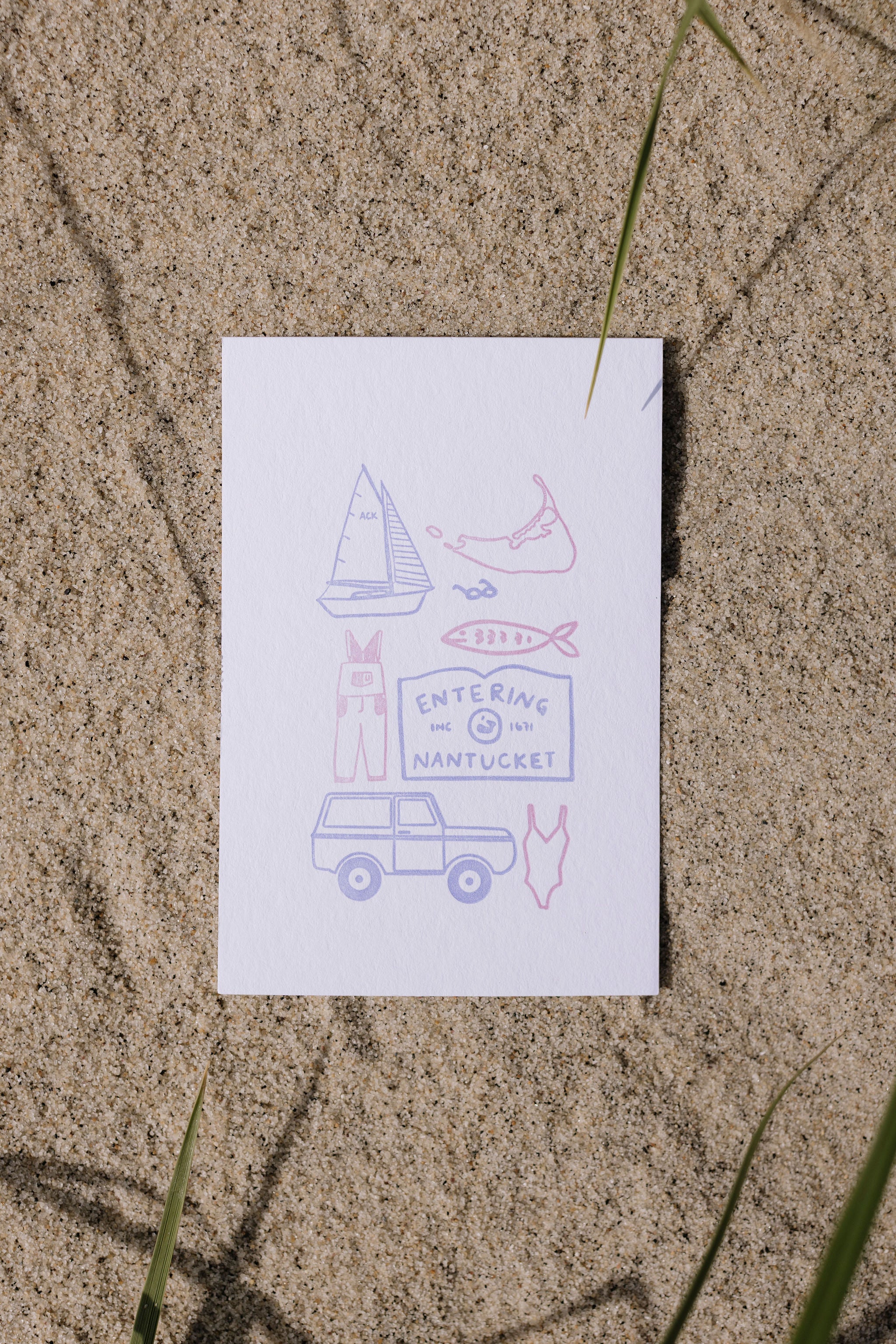 White postcard with colorful illustrations of a sailboat, fish, Nantucket Island and car on a sandy background