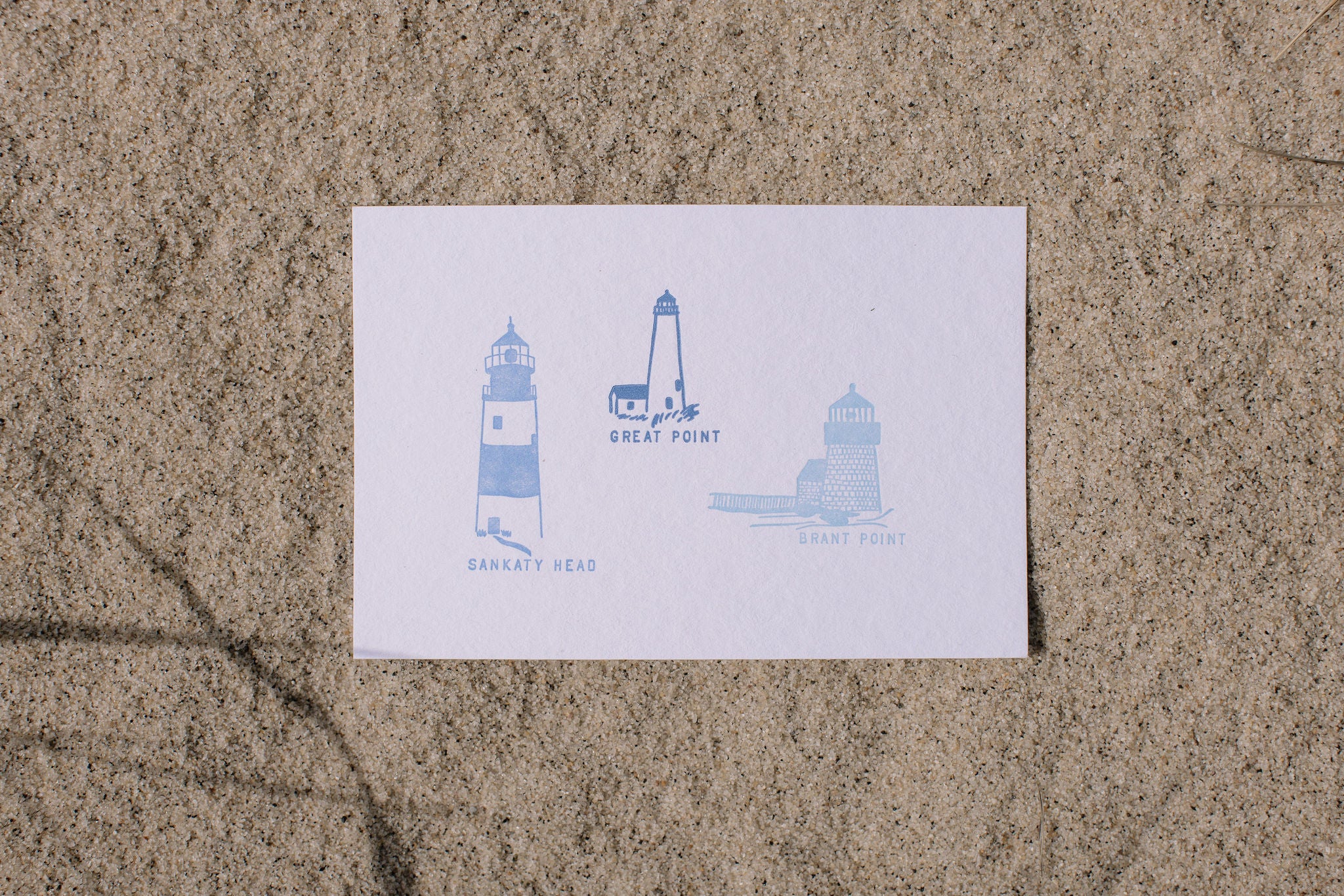 Postcard with blue Nantucket lighthouse illustrations on sand