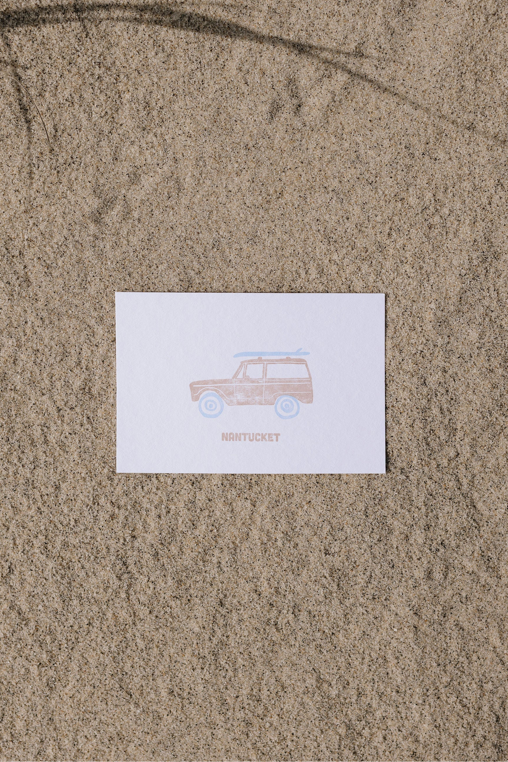 Postcard with an illustration of a Ford bronco with a surfboard on top and 'Nantucket' text on sand
