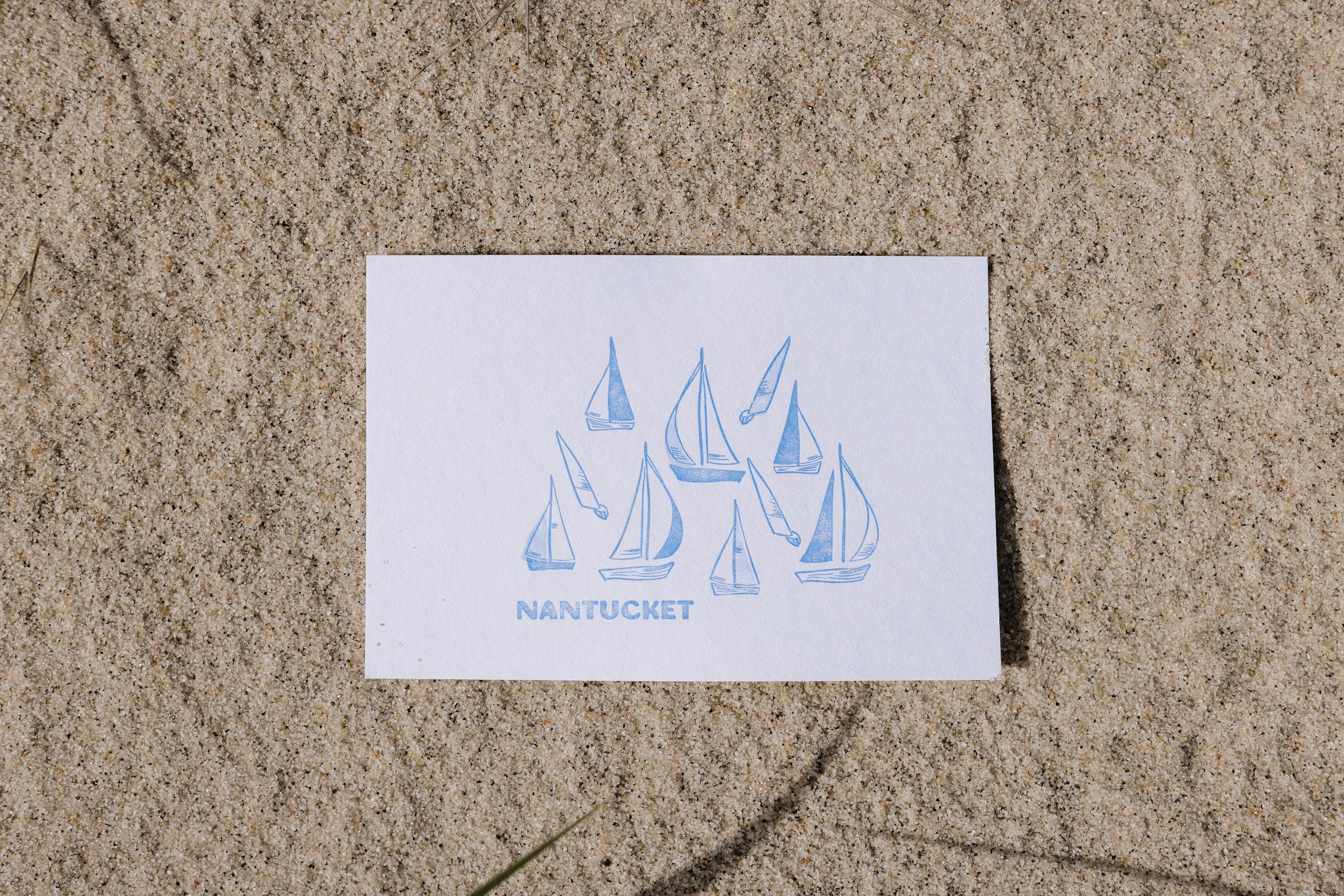 Postcard with sailboat design and 'Nantucket' text on sand