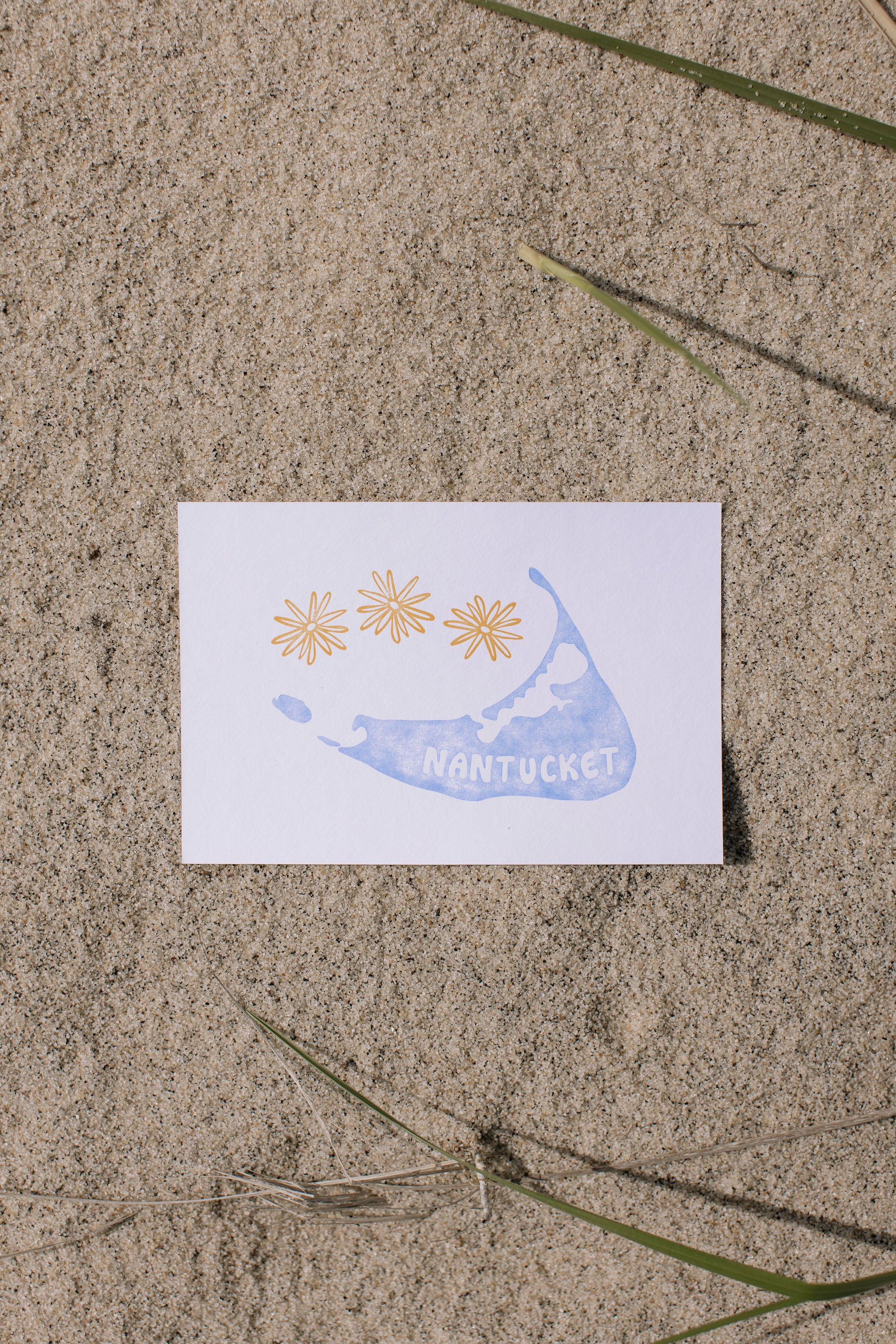 Postcard with a blue Nantucket island illustration and 'Nantucket' text on sand