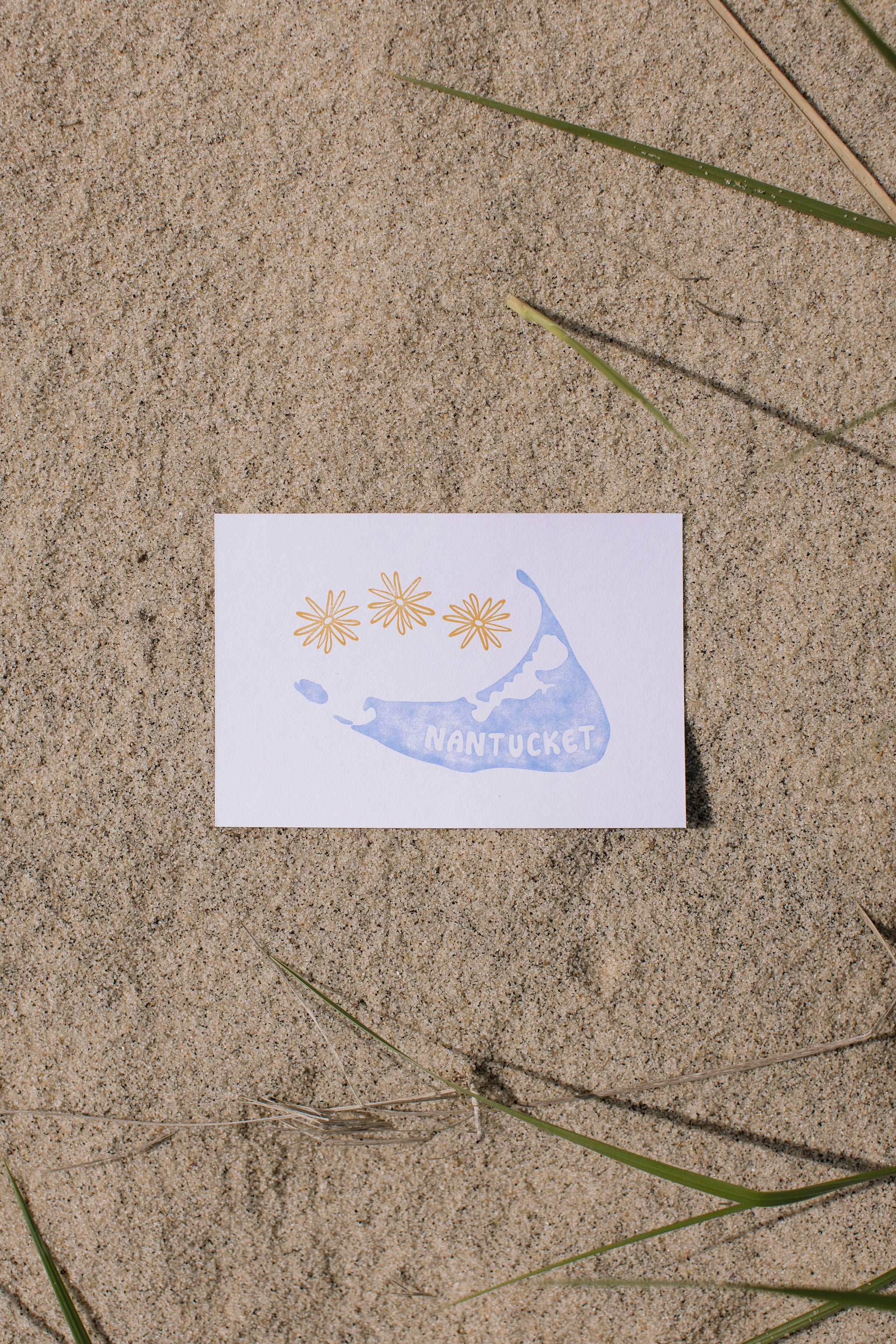 Postcard with a blue Nantucket island illustration and 'Nantucket' text on sand