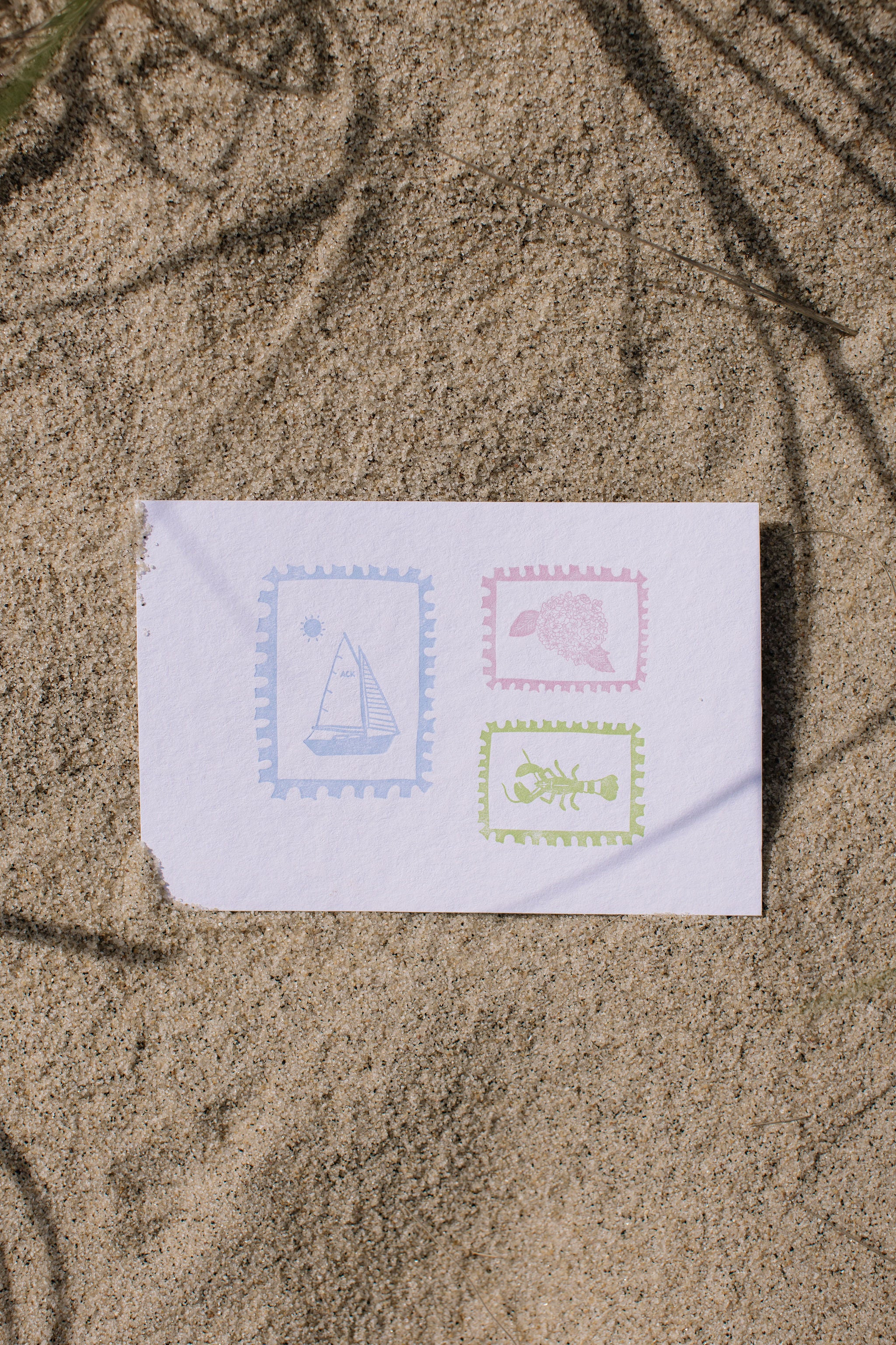 White envelope with letter pressed stamps on sand.