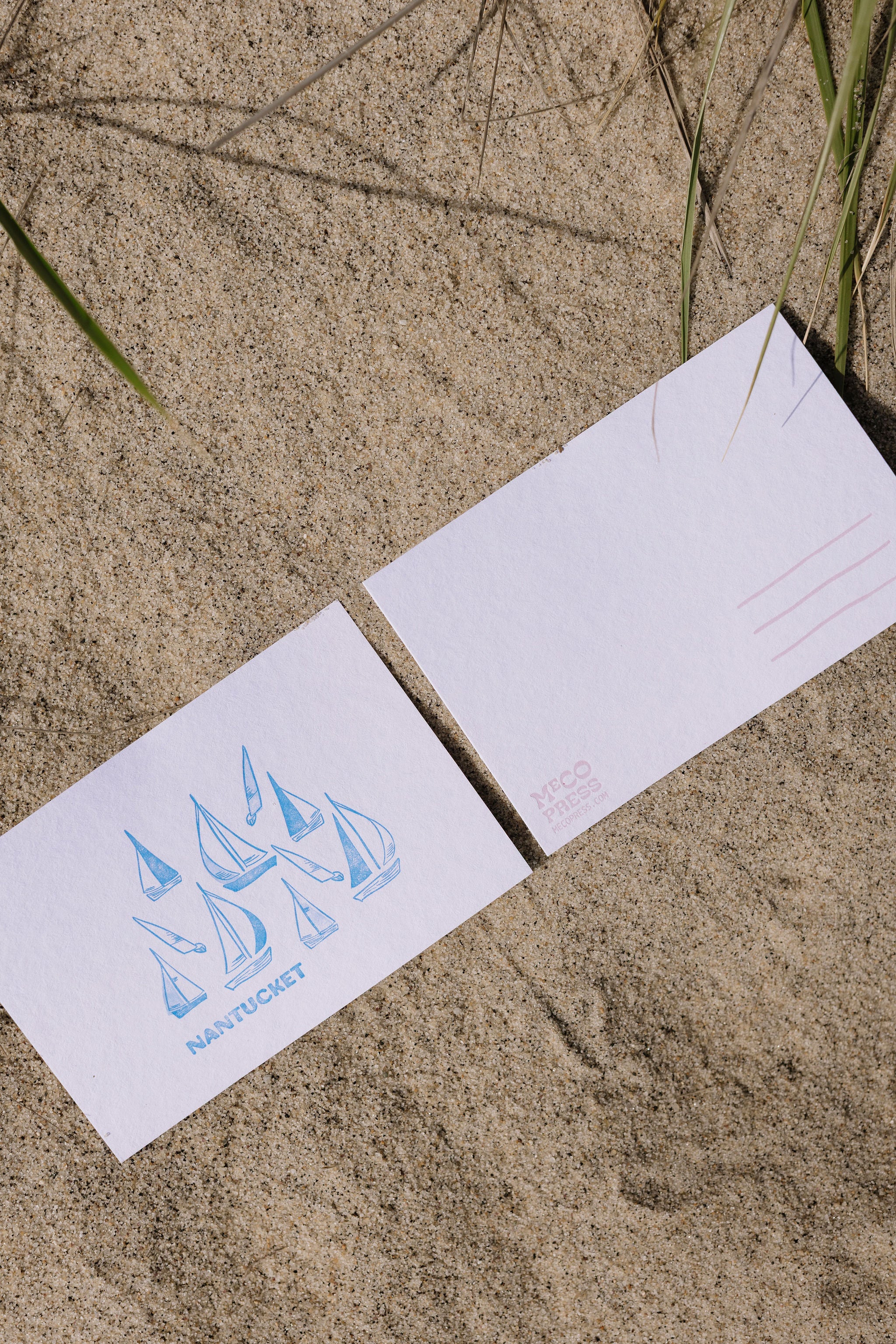 Front and back of a postcards on sand surface