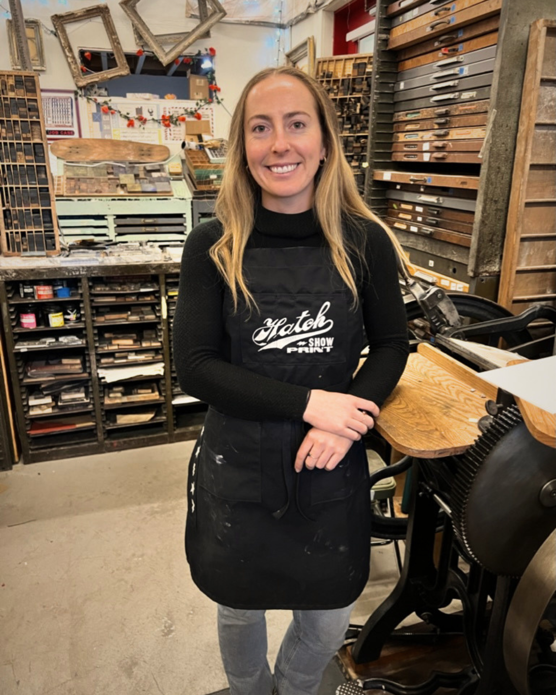 Woman wearing a black apron with text in a workshop setting