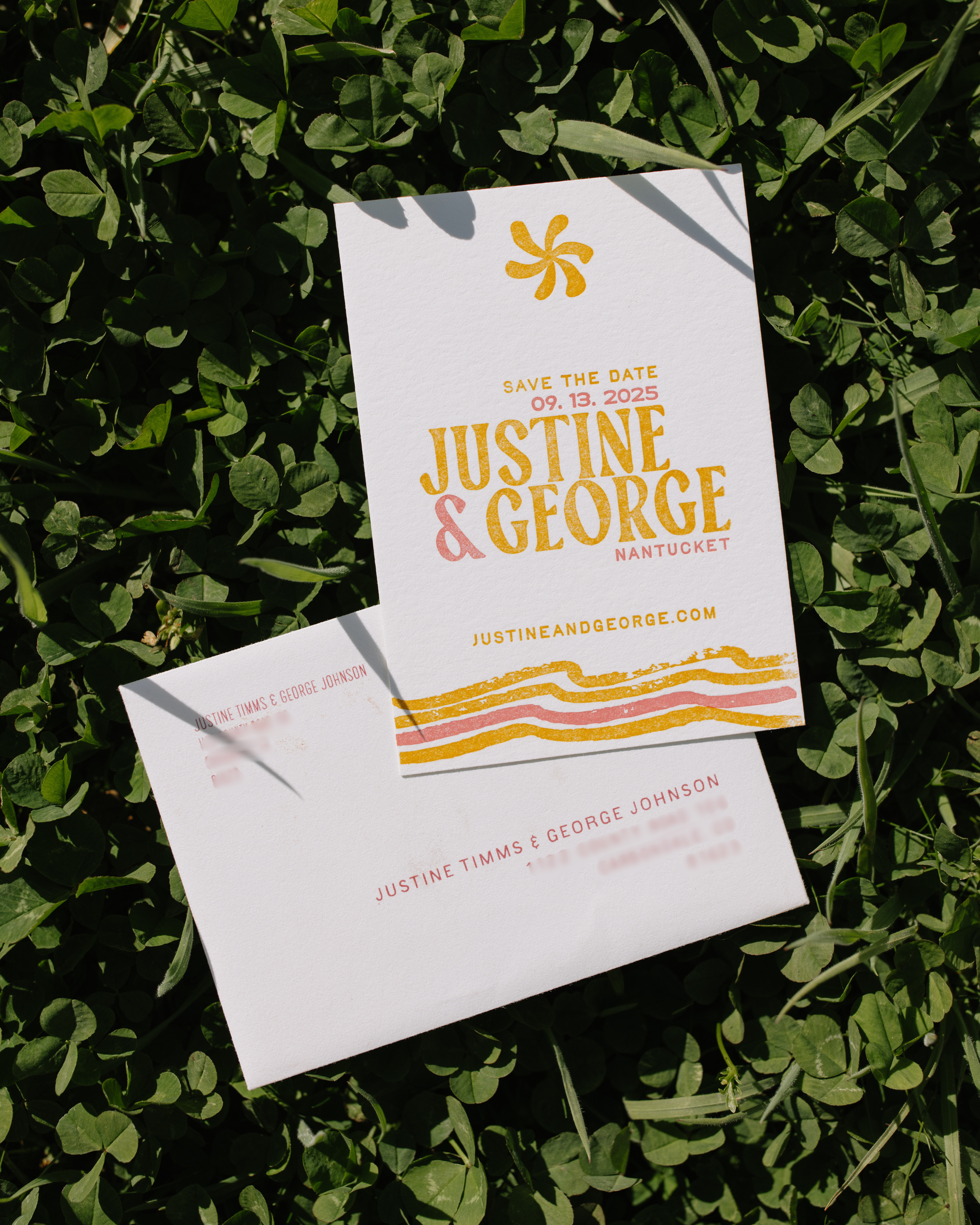 Yellow and pink custom save the date on a green leafy surfacte.