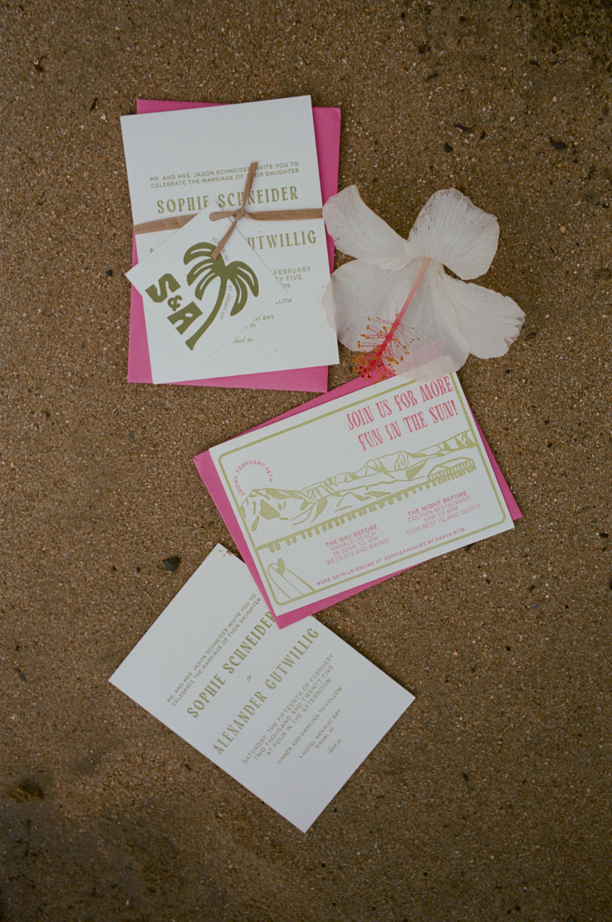 Set of wedding invitations with pink and green design on a sandy beach surface.